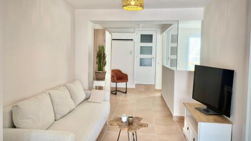 a living room with a white couch and a television at Hotel Abaco Altea in Altea