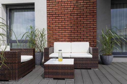 a patio with two wicker chairs and a table at Szczesliwa 13 by Elite Apartments in Starogard Gdański