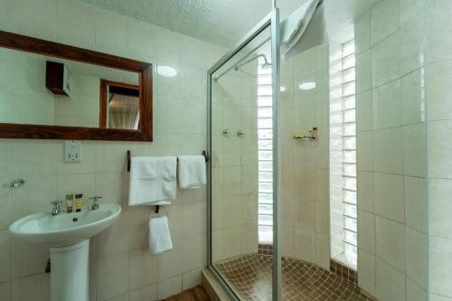 a bathroom with a sink and a glass shower at Kasongo Lodge in Victoria Falls
