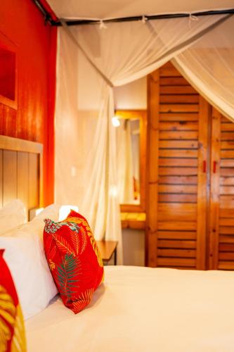a bedroom with a white bed with a red pillow on it at Kasongo Lodge in Victoria Falls
