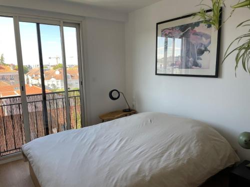 パンタンにあるLovely apartment next to Parisのベッドと大きな窓のある寝室