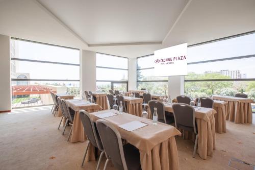 a dining room with tables and chairs and windows at Crowne Plaza Vilamoura - Algarve by IHG in Vilamoura