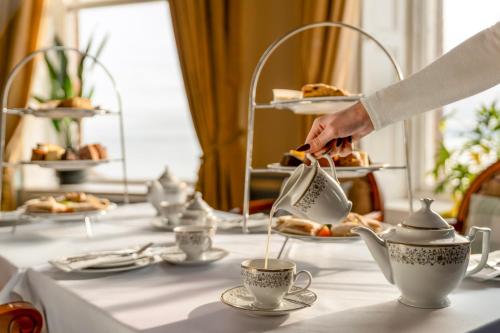 a woman is pouring tea into a tea pot on a table at The Grand Scarborough in Scarborough