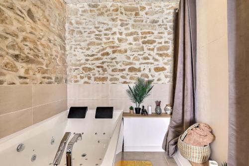 łazienka z wanną i kamienną ścianą w obiekcie Jacuzzi de charme pour 2 w mieście Nîmes