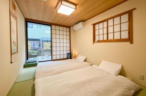 two beds in a room with a window at We Guest House in Tokyo