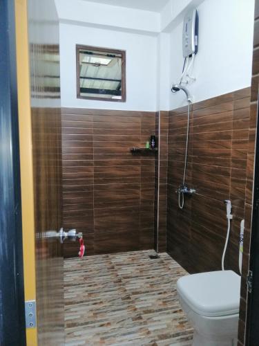 a bathroom with a toilet and a shower with wooden walls at Super View in Ella