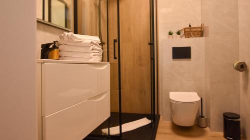 a bathroom with a shower and a toilet and towels at VacationClub - Słoneczne Osiedle Apartament 17 in Ustronie Morskie