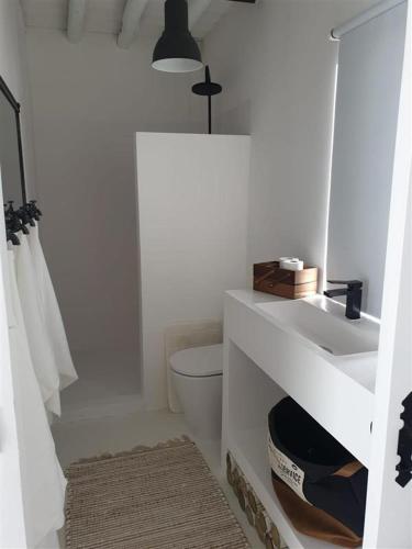 a white bathroom with a sink and a toilet at Casa da Oliveira in Reguengos de Monsaraz