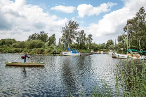a man in a canoe on a river with boats at Ferienhaus Haubenlerche 27 in Fuhlendorf
