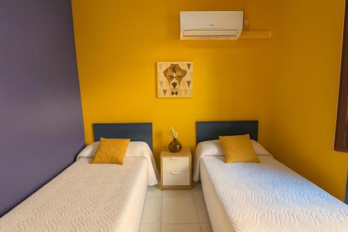 two beds in a room with yellow walls at Casa Antares in Granada