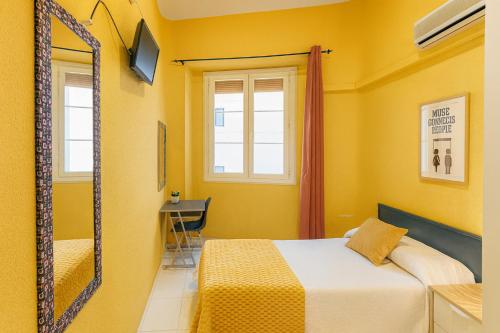 a yellow bedroom with a bed and a mirror at Casa Antares in Granada