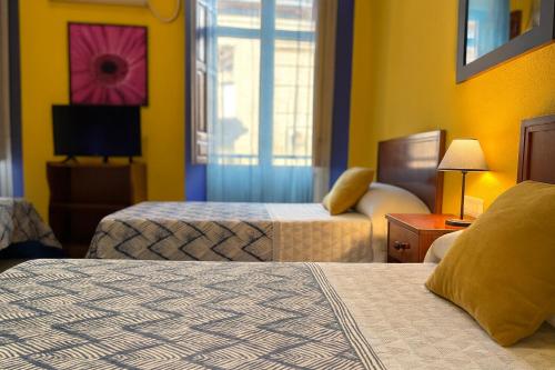 a hotel room with two beds and a window at Casa Antares in Granada