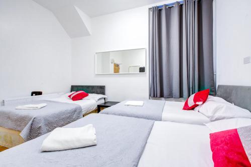 a room with three beds with red pillows at Abbey Hotel in London