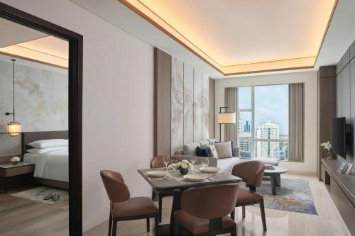 a living room with a bed and a table and chairs at The Mayflower, Jakarta-Marriott Executive Apartments in Jakarta