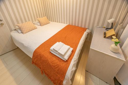 a small bedroom with a bed with an orange blanket at KOSUMOSU Ikebukuro Shinjuku Private House in Tokyo