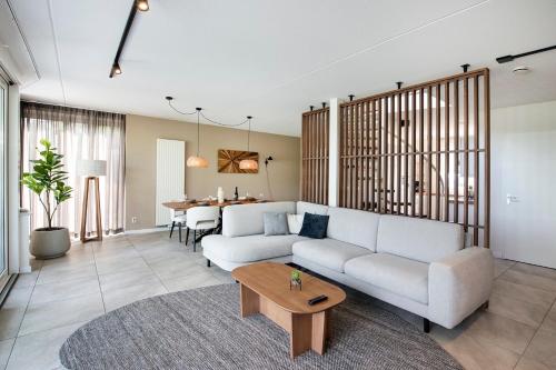 a living room with a white couch and a table at Resort Boschmolenplas in Heel