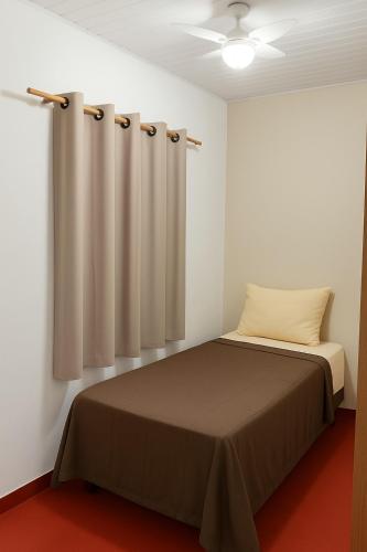 a bedroom with a bed and a curtain at Pousada e Alojamento Recanto São José hospedagem econômica em Rio Verde in Rio Verde
