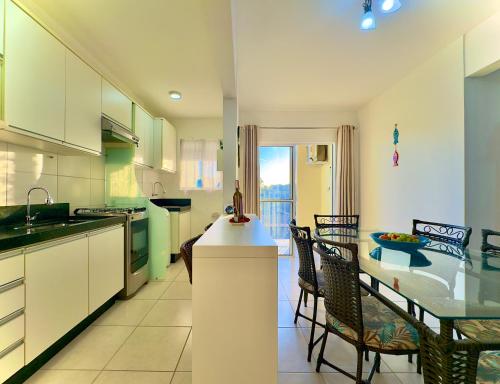 a kitchen and dining room with a table and chairs at Apto em Barra Velha 340m da PRAIA com SACADA com CHURRASQUEIRA, AR CONDICIONADO WI-FI, PISCINA, PORTARIA 24h, ACADEMIA MINI MERCADO e vaga de GARAGEM in Barra Velha