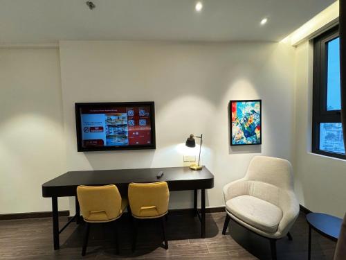 une pièce avec un bureau et deux chaises et une télévision dans l'établissement The Sapphire City Park, à Hạ Long