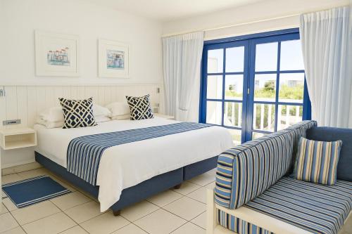 a bedroom with a bed and a couch and a window at Kaliva 136 Club Mykonos, Langebaan in Langebaan