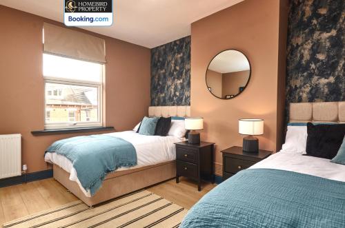 a bedroom with two beds and a mirror at Beautiful 3BDR House By Homebird Property Management Short Lets & Serviced Accommodation Leeds With Free Parking & Free WiFi in Leeds