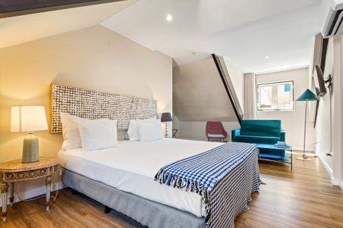 a bedroom with a large bed and a blue chair at Casa do Patio by Shiadu in Lisbon