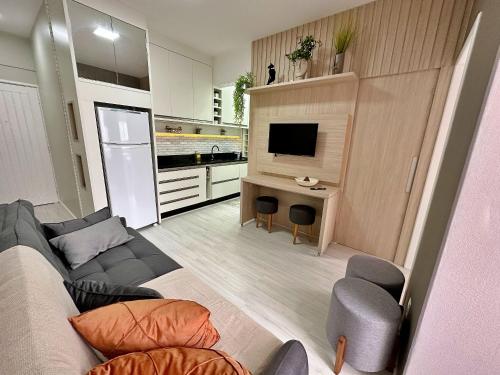 ein Wohnzimmer mit einer Couch, einem Tisch und einem Fernseher in der Unterkunft Home 403 - Studio sofisticado no centro de Floripa in Florianópolis