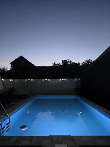 a swimming pool lit up at night at Apartman Crvenka bazen in Crvenka