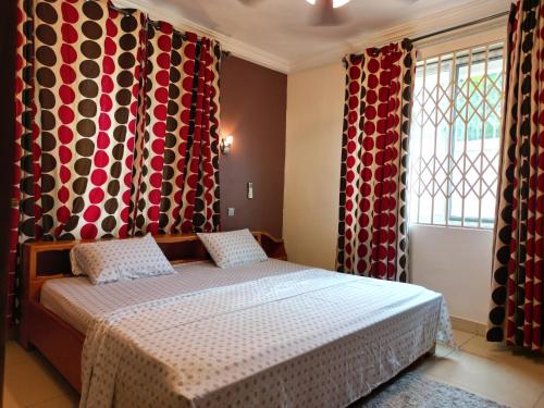 Un dormitorio con una cama y dos ventanas con cortinas. en Kadny Villa, en Accra