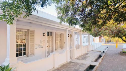 a white building with shuttered windows on a street at River Bend Guesthouses in Graaff-Reinet