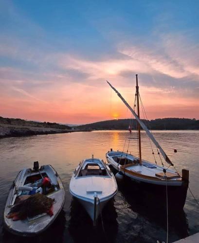 three boats are docked in the water at sunset at House FIDULIĆ - apartment RUSTIC in Lumbarda
