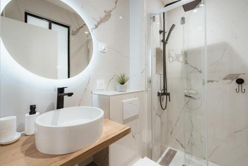 une salle de bain blanche avec un lavabo et un miroir dans l'établissement Cosy studio près du Panthéon, à Paris