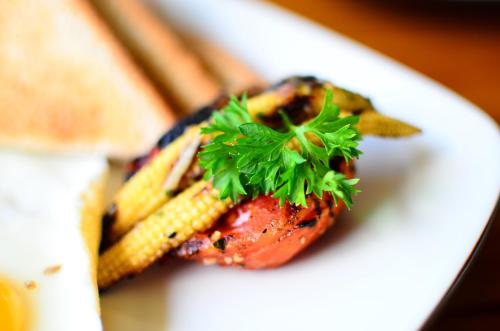 ein weißer Teller mit einem Stück Fleisch und Mais in der Unterkunft Pesantian Villa and Warung in Ubud