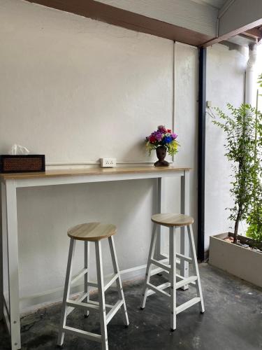 a counter with two stools and a vase of flowers at baan in kan homestay&cafe kanchanaburi city in Kanchanaburi City