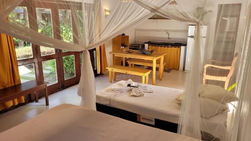 a bedroom with a canopy bed and a desk and a table at Aconchego em Barra Grande in Marau