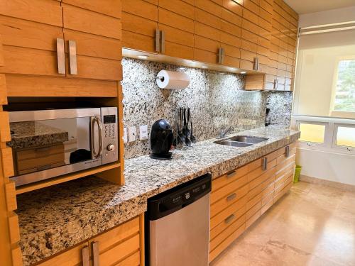 a kitchen with a sink and a microwave at ANANA El Dorado 305 | Pool & Lake Views in Ajijic
