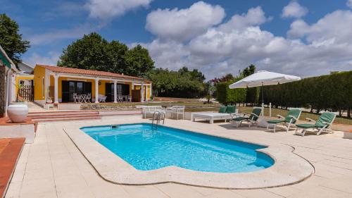a swimming pool with chairs and a house at Vinha da Quinta in Sintra