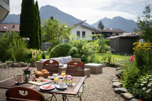 een tuin met een tafel en stoelen waarop eten staat bij Alma Hotel Oberstdorf in Oberstdorf