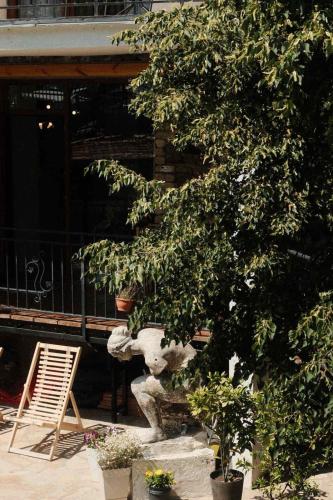 a tree in front of a building with a chair at Mood Hotel Kazbegi in Stepantsminda