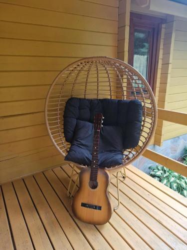 a guitar sitting in a wicker chair with a guitar at Siedlisko Sapunki dom z duszą rybaka na Warmii in Bogdany