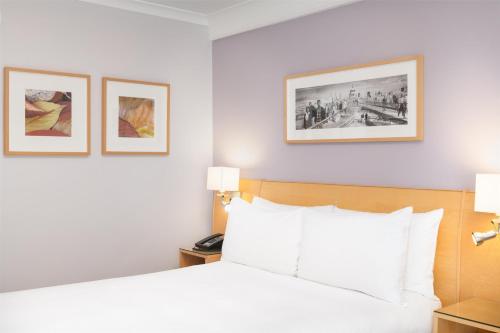 a hotel room with a bed and two pictures on the wall at Hilton London Kensington Hotel in London
