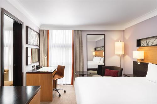 a hotel room with a bed and a desk at Hilton London Kensington Hotel in London