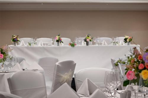 a room with white tables and chairs with flowers at Hilton London Kensington Hotel in London