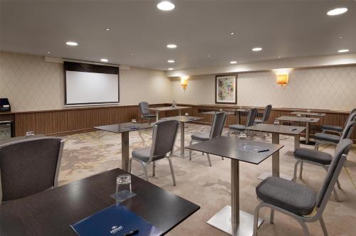 a conference room with tables and chairs and a screen at Hilton London Kensington Hotel in London