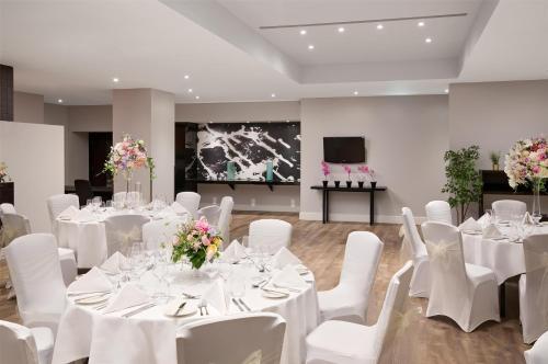 a banquet hall with white tables and white chairs at Hilton London Kensington Hotel in London