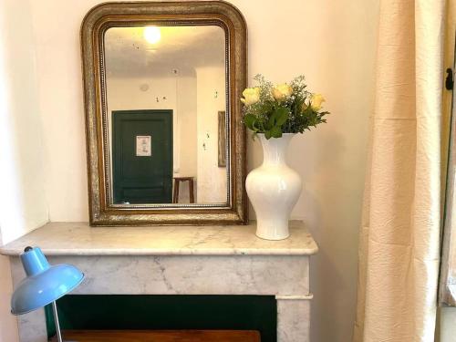 a mirror and a vase with flowers on a fireplace at Villa Magdala Arts & Résidence in Hyères