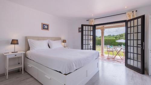 a white bedroom with a bed and a balcony at Vinha da Quinta in Sintra