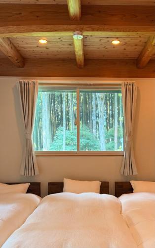 two beds in a bedroom with a window at Nishihara Village, Aso District, near the Airport MACOMO in Koga