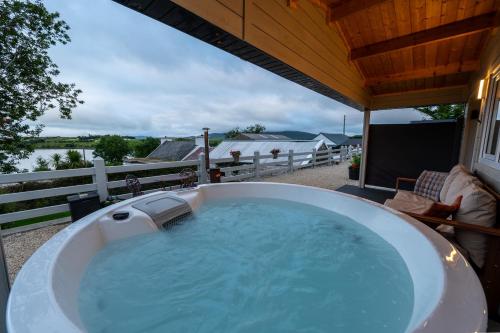 a large hot tub on a patio with a view of the water at Luxury Log Cabin with Private Hot Tub & Sea Views in Letterkenny
