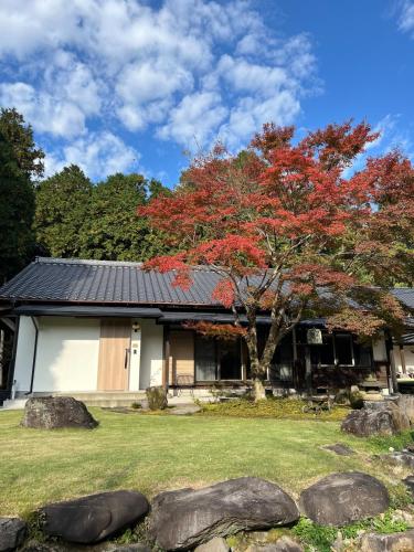a house with a red tree in front of it at Nishihara Village, Aso District, near the Airport MACOMO in Koga